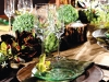 This rustic arrangement is given a modern twist as pronounced candles and an assortment of foliage complement slender stemware and transparent plates.
